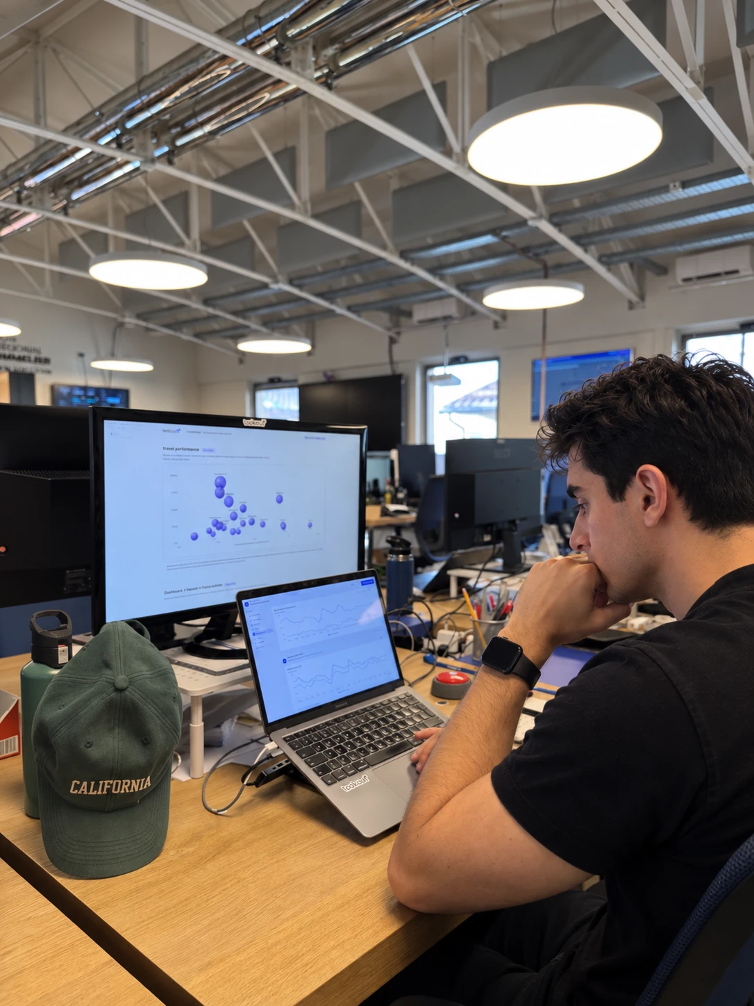 A Grabll team member at his desk studying performance charts on a monitor and a laptop.